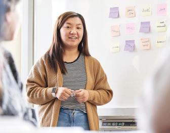 A student stands in front of a class giving a presentation